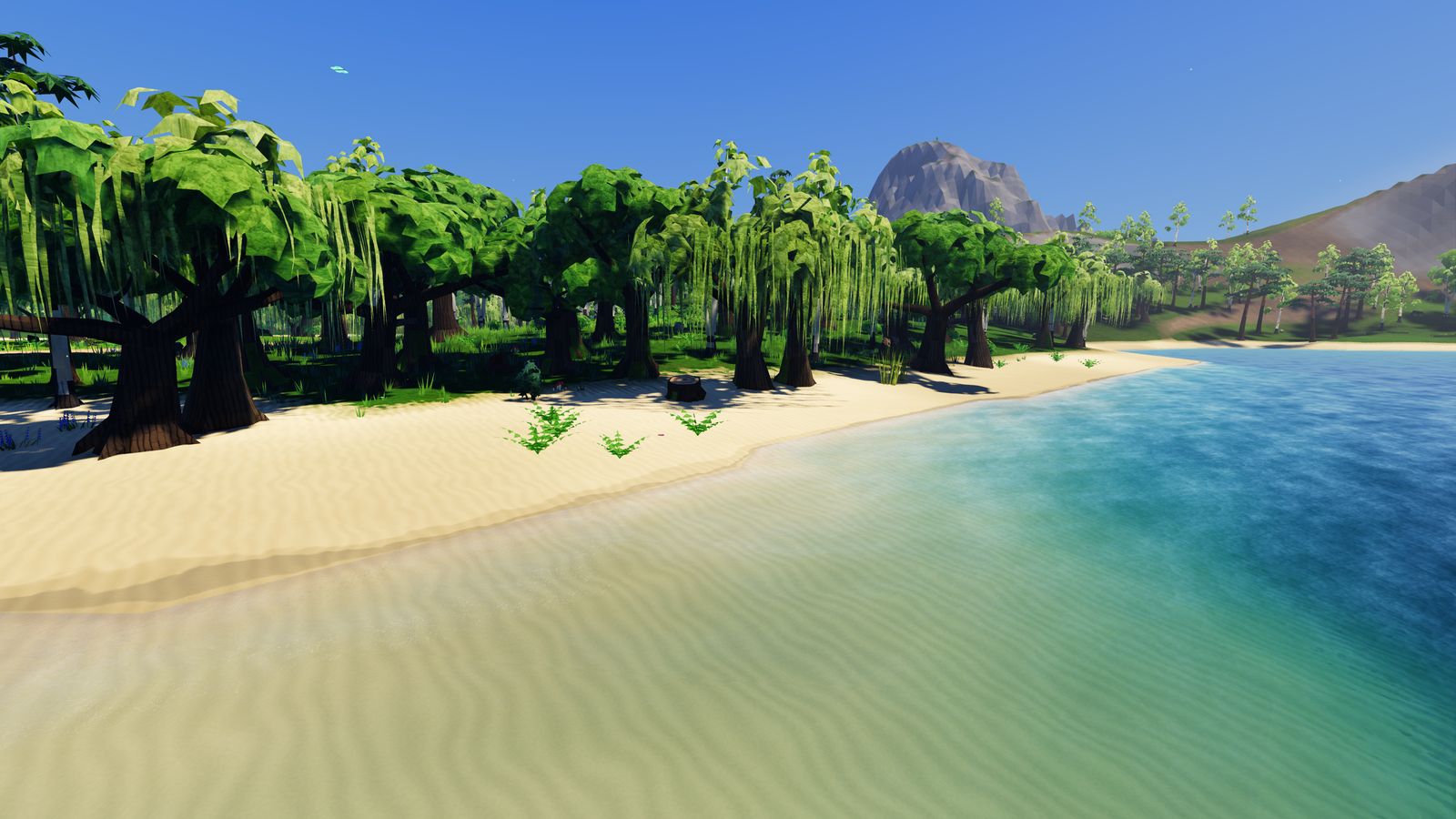 A sandy lake shore with clear water under a blue sky.